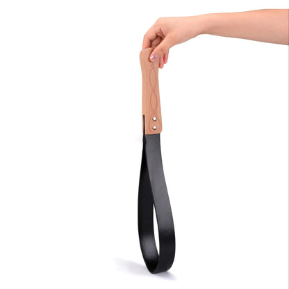 Black leather BDSM paddle with wood handle on white background